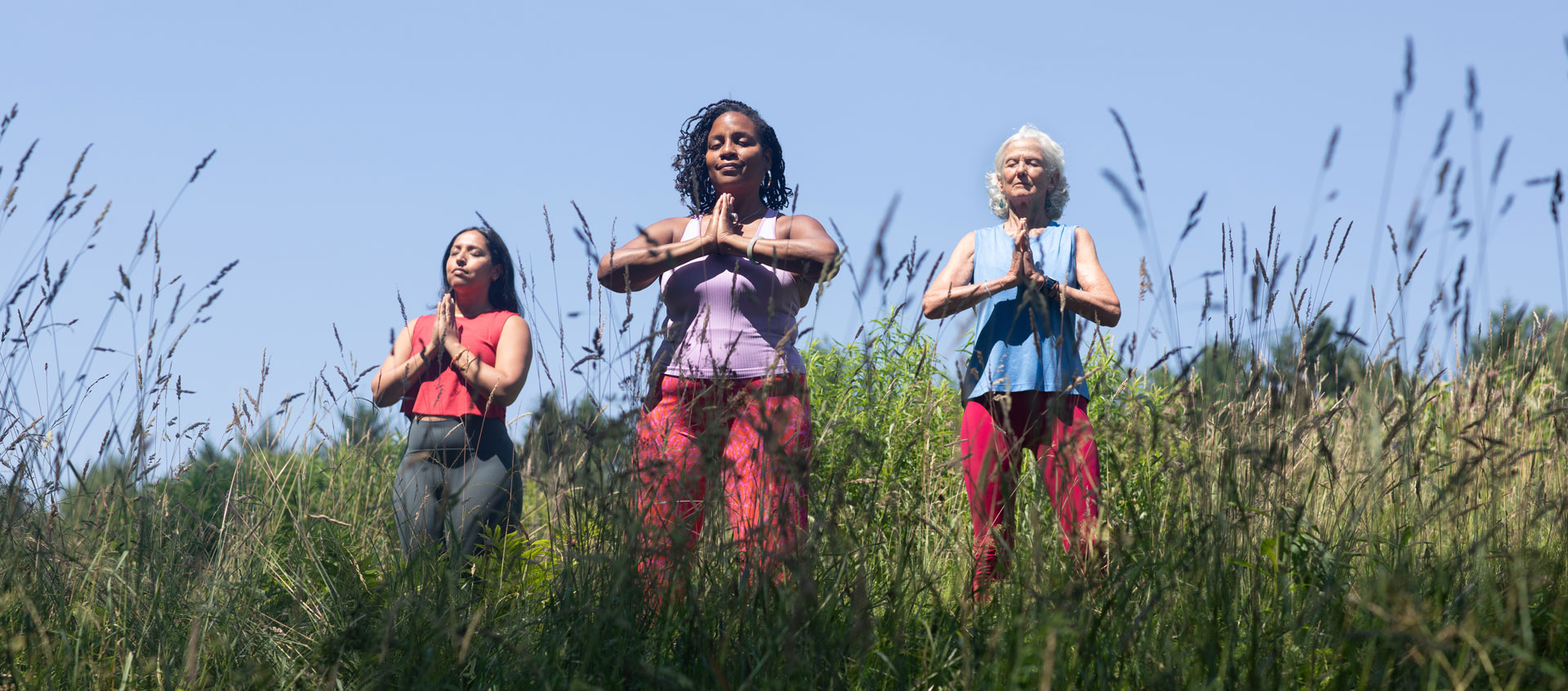 three women with hands in prayer outside