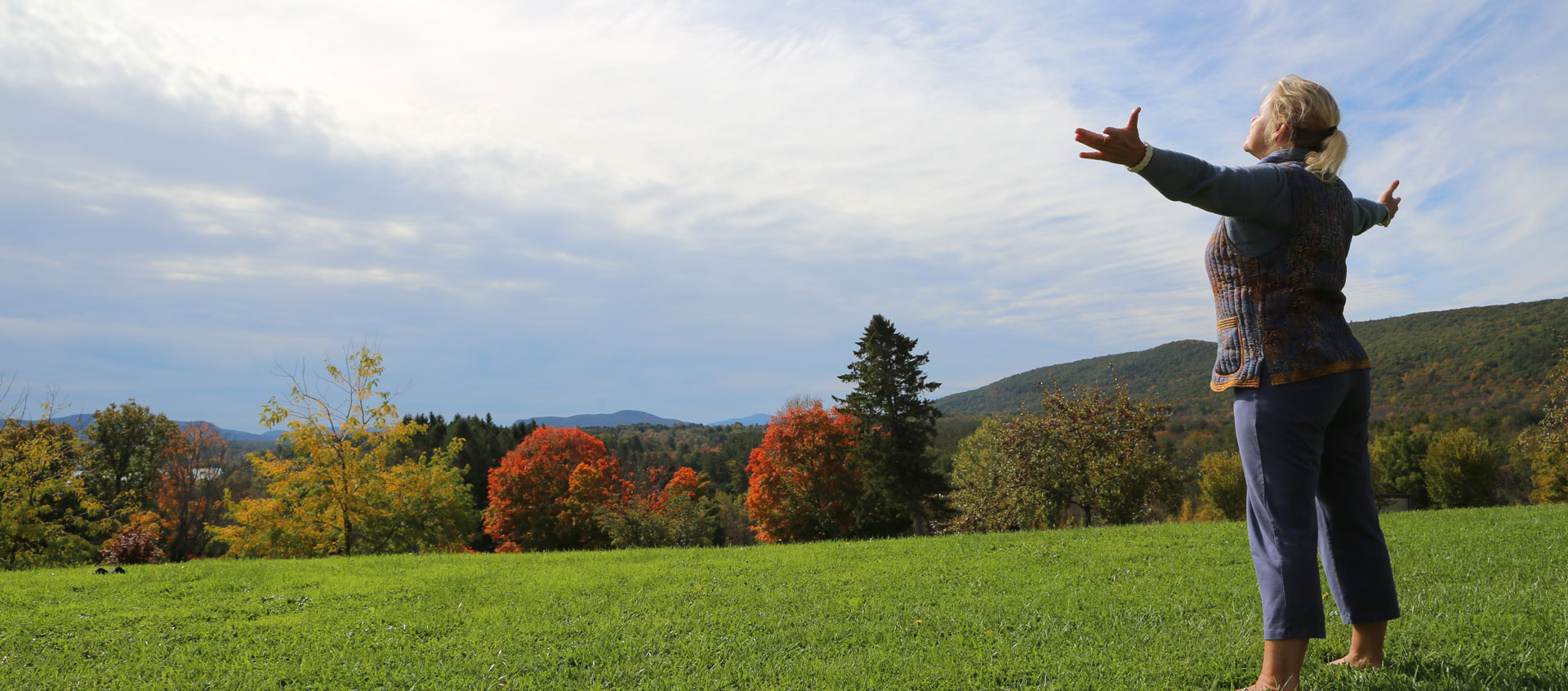 woman standing in field with arms outstretched