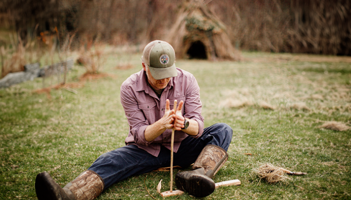 Micah Mortali starting a fire using a stick.